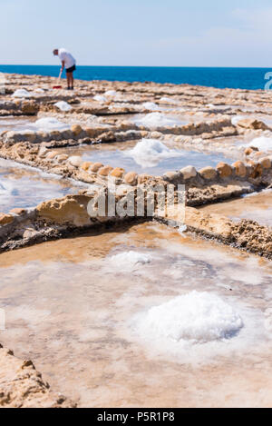 Harvesting sea salt from the ancient salt pans in Marsalforn, Gozo, Malta. Stock Photo