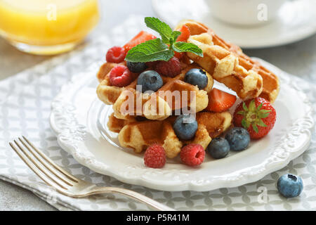 Fresh homemade waffles with raspberries, strawberries, blueberries and honey. Delicious Breakfast with berries. Selective focus Stock Photo