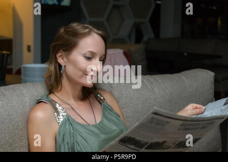 https://l450v.alamy.com/450v/p5r9pd/young-beautiful-elegant-woman-in-evening-dress-sitting-at-restaurant-and-reading-menu-or-newspaper-attractive-caucasian-girl-relaxing-on-sofa-at-cafe-p5r9pd.jpg