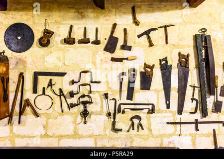 Old traditional tools hanging on a wall in a woodworking workshop. Stock Photo