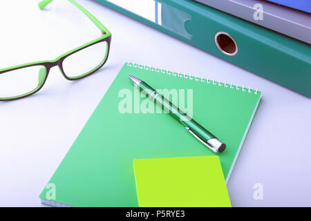 Work place table with folders file on it and modern laptop, pen, glasses and textbook lying near on a white background Stock Photo