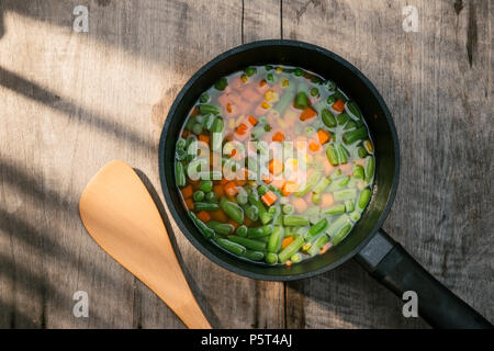 Vegetable stew in black pot on color napkin on wooden background Stock Photo