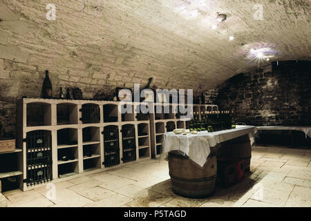 Tasting room in the wine cellar, along the walls there are shelves with bottles of wine. In the center of the room - tables in the form of barrels Stock Photo