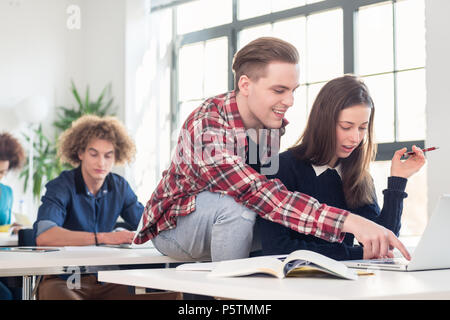 Two cheerful millennial students laughing while sitting together Stock Photo