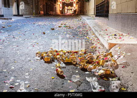 Beer tins and plastic cups litter the street along with ticker tape after a Roman Catholic religious parade, Xwekija, Gozo, Malta Stock Photo
