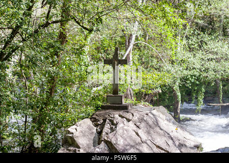 stone cross on top of a mound in a river Stock Photo