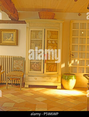 Trompe-l'oeil scene painted on doors of old cupboard in French country hall with large ceramic pot Stock Photo