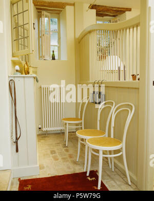 Cream Bentwood chairs in cream kitchen in open-plan converted stable Stock Photo