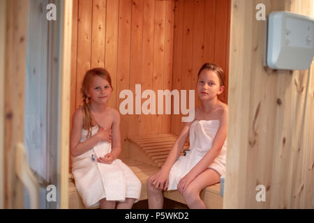 Two girls have wrapped themselves in towels and are sitting in a