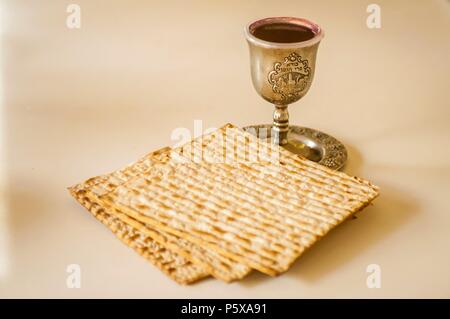 Jewish holidays concept image: Passover (Pesach) matzah and a silver cup full of wine with a traditional blessing 'Borei Pri HaGafen' engraved on it. Stock Photo