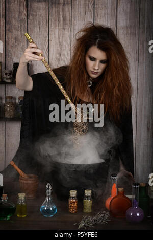 witch stirring her magic potion with her wand Stock Photo