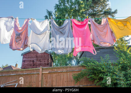 Clothes hanging on a washing line in a residential garden to dry. Stock Photo