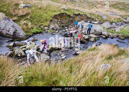 Group of hikers crossing Afon Llafar River in Carneddau mountains of Snowdonia National Park seen from above.  Bethesda, Gwynedd, Wales, UK, Britain Stock Photo