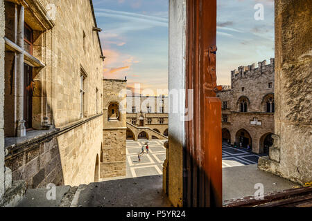 View from a window as tourists walk the courtyard of the Palace of the Grand Master of the Knights of Rhodes on the island of Rhodes Greece Stock Photo