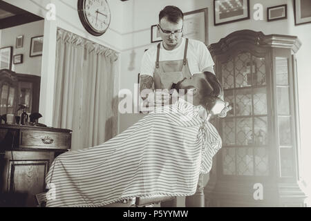 Barber during work in his barber shop. Picture in black and white stylization Stock Photo