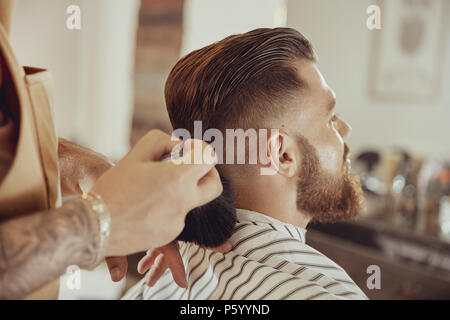 Barber shakes hair off from the client's neck.  Photo in vintage style Stock Photo