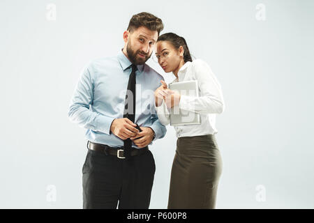 The young woman whispering a secret behind her hand over white background Stock Photo