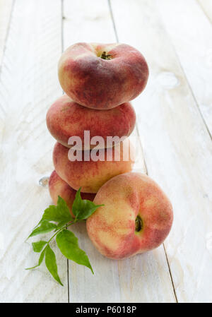 Saturn peaches or UFO, donut, flat peaches on white wood boards Stock Photo