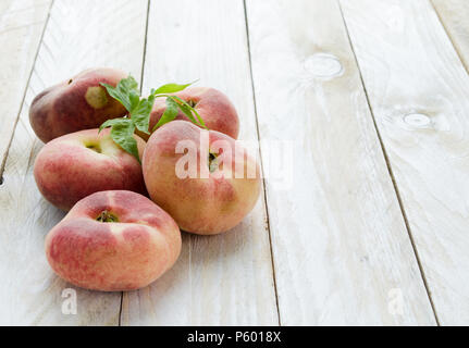 Saturn peaches or UFO, donut, flat peaches on white wood boards Stock Photo