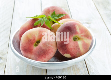 Saturn peaches or UFO, donut, flat peaches on white wood boards Stock Photo