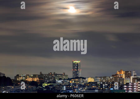 Full moon shines bright over urban homes and apartments in Osaka, Japan Stock Photo