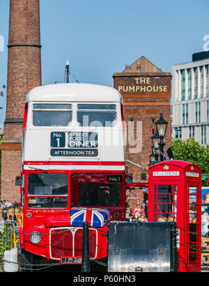 Traditional red London bus and British red telephone box, Albert Dock, Liverpool, England, UK with brick Pumphouse pub and brick tower in background Stock Photo