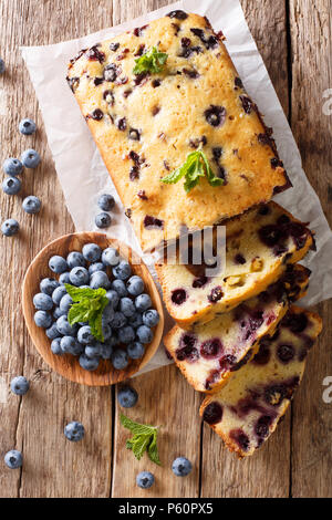 Dessert sliced fresh blueberry bread muffin cake with mint closeup on the table. vertical top view from above Stock Photo