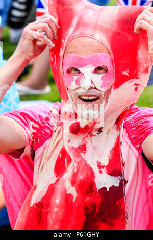 Portrait, man from Bacon Butty Brigade team covered in custard, smiling giving fist to head salute after battle at custard pie championships. Stock Photo