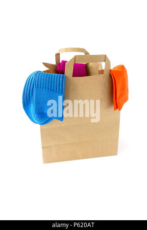 Three pair of modern, vibrant colored socks hanging over the top of a paper bag. Stock Photo