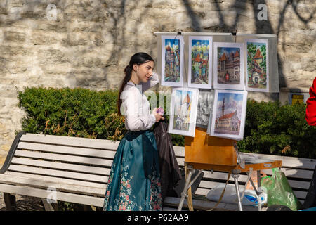 Young woman exposing artwork on the street, Tallin, Estonia Stock Photo