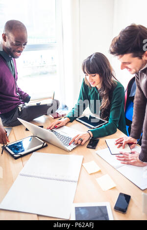 three young multiethnic business people working together using technological devices - trading, business, technology concept Stock Photo