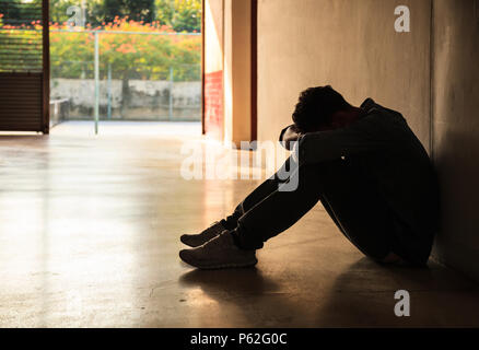 Emotional moment: man sitting holding head low on knees, stressed sad young male having mental problems, feeling bad, depressed, disappointed, hopeles Stock Photo