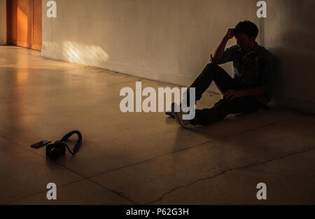Emotional moment: man sitting holding head by hand, stressed sad young male having mental problems, feeling bad, depressed, disappointed, hopeless. De Stock Photo