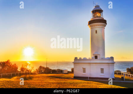 Warm filling sun light rising above open sea horizon off Pacific ocean behind Norah head lighthouse on Australian's central coast. Stock Photo