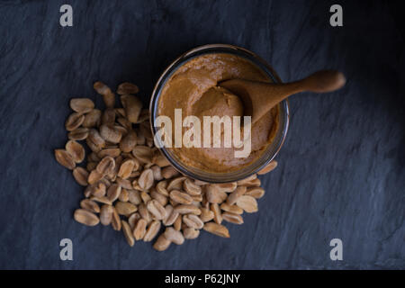 Bowl of peanut butter and peanuts on dark background Stock Photo