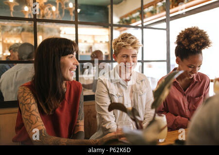 Smiling young female friends talking together in a trendy bistro Stock Photo