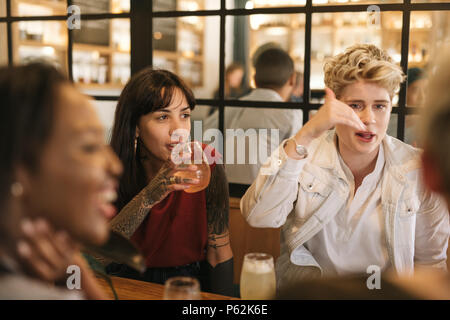 Diverse young girlfriends hanging out together in a trendy bistro Stock Photo