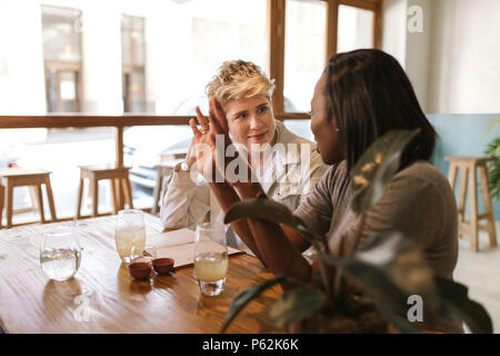 Waiter talking with customers seated at a bistro table Stock Photo