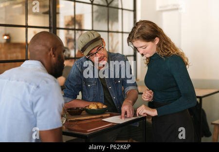 Waitress explaining the menu to customers in a bistro Stock Photo