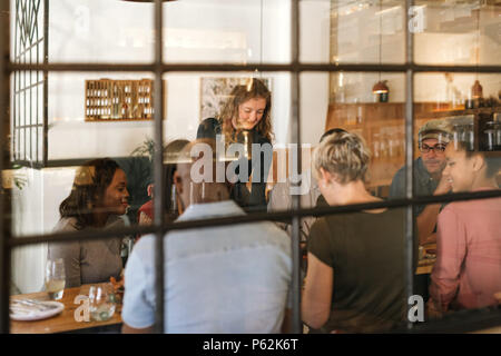 Waitress serving food to smiling customers in a bistro Stock Photo
