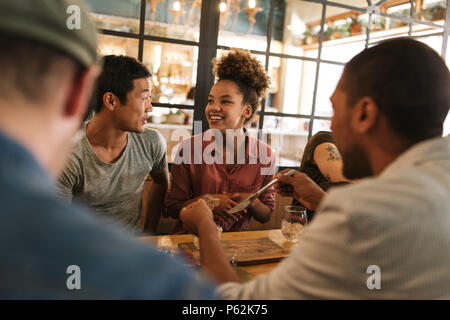 Smiling young friends talking together over a bistro dinner Stock Photo