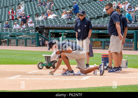 Detroit, Michigan - Three members of the grounds crew watch as one scrubs home plate before a baseball game at Comerica Park, home of the Detroit Tige Stock Photo
