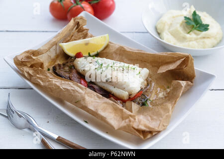 Cod fillets baked in parchment paper with vegetables Stock Photo