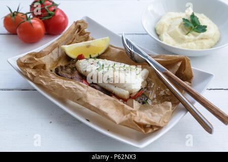 Cod fillets baked in parchment paper with vegetables Stock Photo