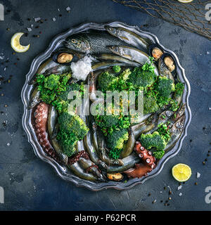 Variety of fresh seafood on a plate with green vegetables Stock Photo