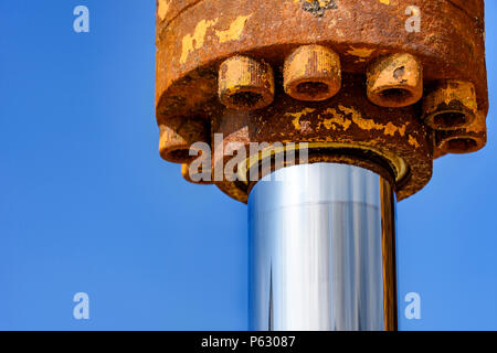 Detail of hydraulic gear with rust on a tractor with blue sky at background Stock Photo