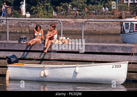 Two women sitting on a jetty chatting, Oulton Broad, Suffolk, England, 1975 Stock Photo
