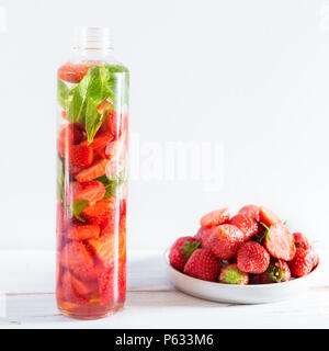 Detox Infused Water with Strawberries and Mint in Sports Bottle with Strawberries nearby on Light Background Stock Photo