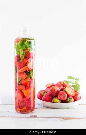 Detox Infused Water with Strawberries and Mint in Sports Bottle with Strawberries nearby on Light Background Stock Photo