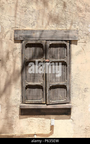 Old wood framed shuttered window with a lock, set in an adobe wall Stock Photo